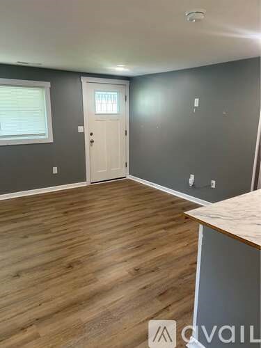 A room with a white door and wooden flooring.