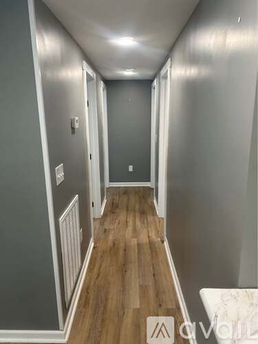 A long hallway with wood floors and white walls.