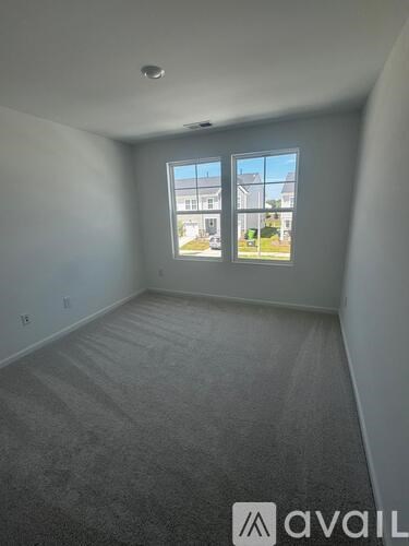 A room with a carpeted floor and a window showing a view of a building and trees.