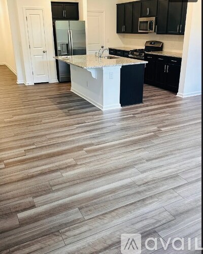 A kitchen with black cabinets and a white island.