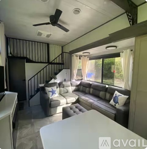 A living room with a couch, a table, and a ceiling fan.