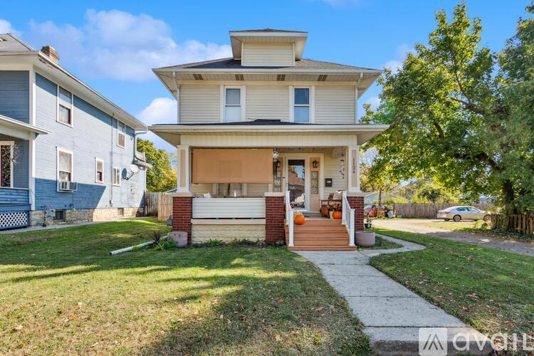 A house with a front porch and a tree in front.