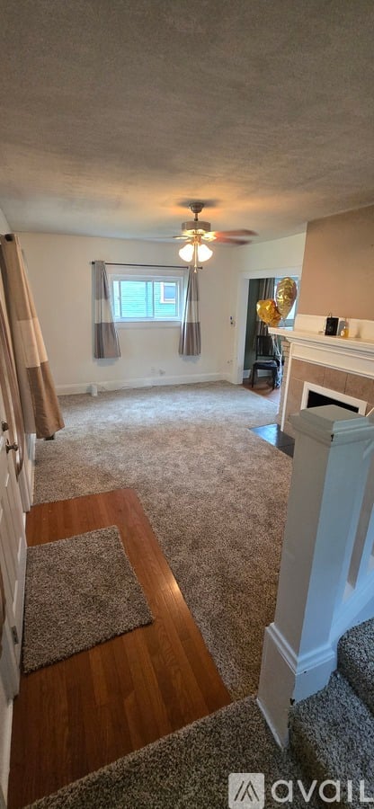 A living room with a fireplace and a rug on the floor.