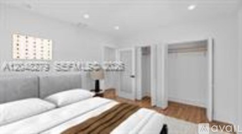 A white bedroom with a large bed and a window.