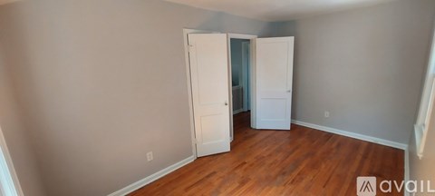 A room with wooden floors and two white doors.