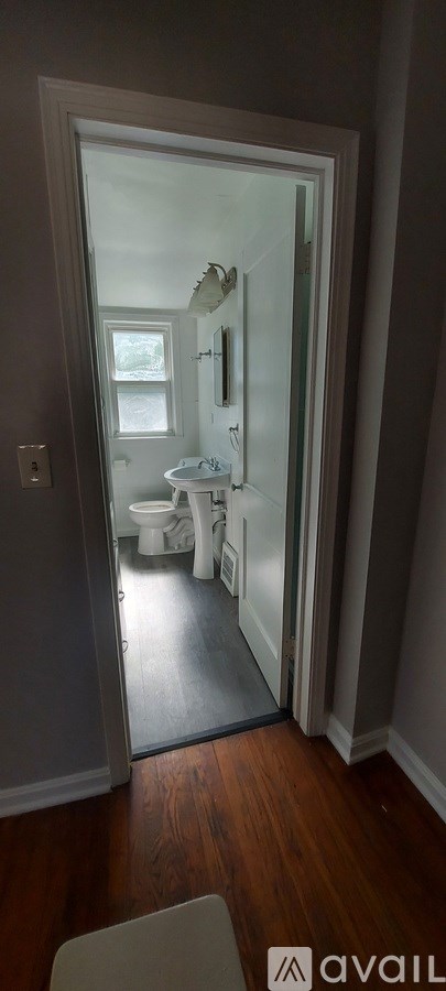 A bathroom with a toilet, sink and mirror.