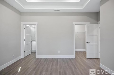 A spacious room with a wood floor and white walls.