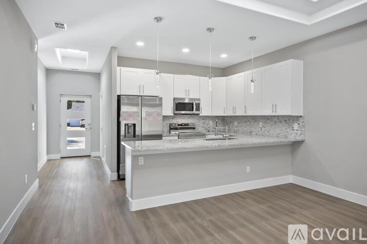A modern kitchen with white cabinets and a marble backsplash.