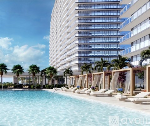 A large hotel with a pool and palm trees.