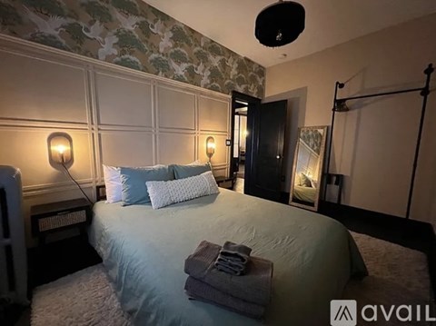 A bedroom with a large bed and two wall lamps.