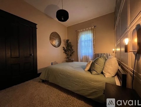 A bedroom with a bed, a Christmas tree, and a wall-mounted light fixture.