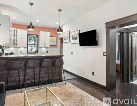 A modern kitchen with a bar area and a television mounted on the wall.