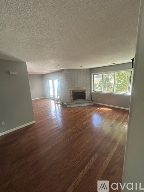 A living room with wood flooring and a fireplace.