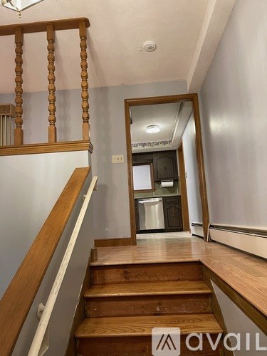 A wooden staircase with a white railing leads to a hallway.
