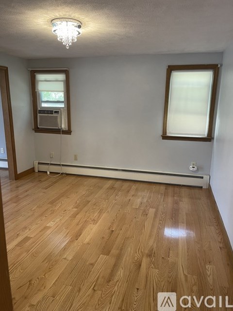 A room with wooden floors and two windows.