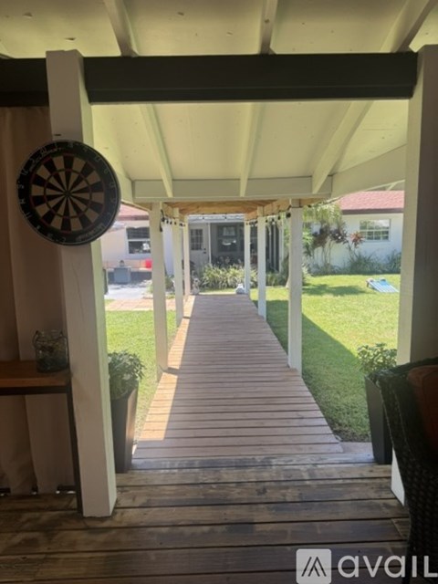 A dartboard is mounted on a wall on the left side of a covered walkway.