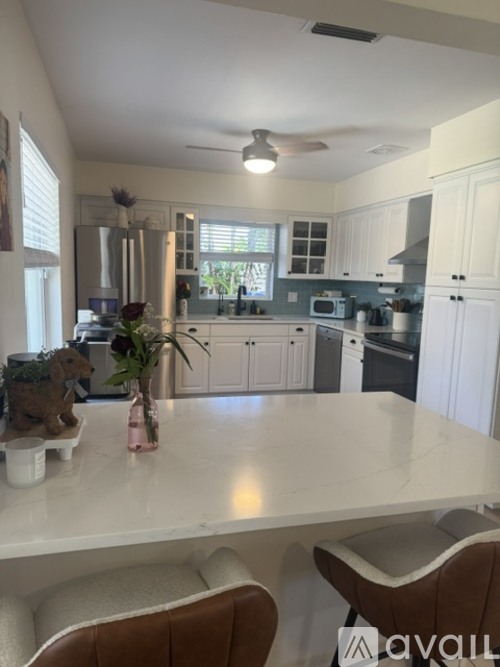 A kitchen with white cabinets and a marble countertop.