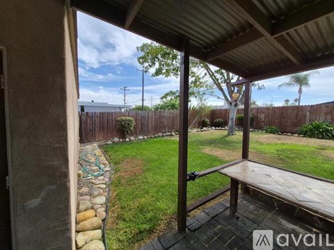 A patio with a table and a bench is covered by a roof.