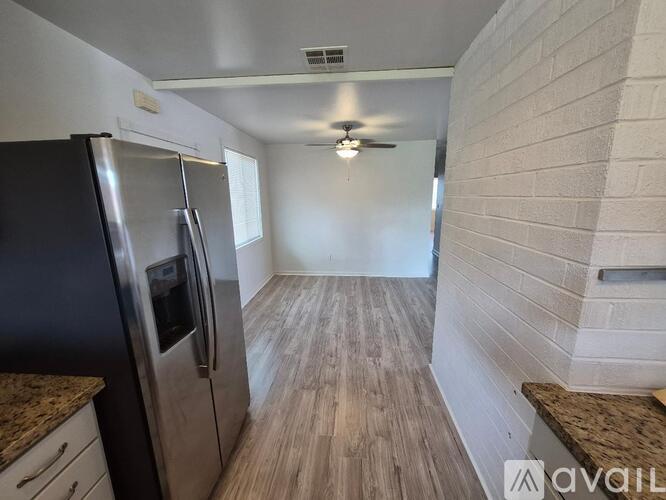 A kitchen with a stainless steel refrigerator and wooden flooring.