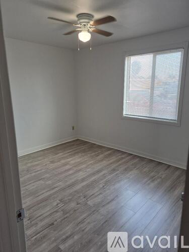 A room with a ceiling fan and a window with blinds.
