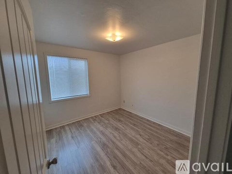 A room with a window and wooden flooring is available for rent.