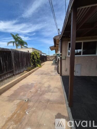 A narrow alley with a wooden fence on the left and a building on the right.