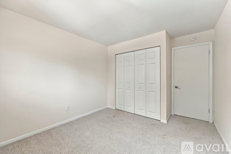 A bedroom with a white door and a white wardrobe.