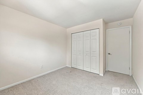 A bedroom with a white door and a white wardrobe.