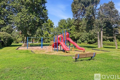 A playground with a red slide and a blue swing set.
