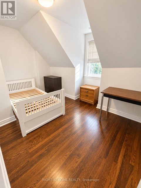 A bedroom with a bed, dresser, and desk.