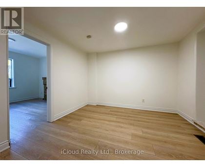 A room with wooden flooring and white walls, with a doorway leading to another room.