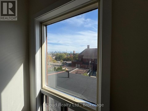 A window with a view of a street and houses outside.