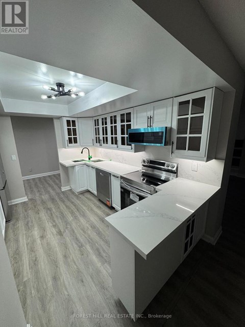 A kitchen with a white counter top and grey cabinets.