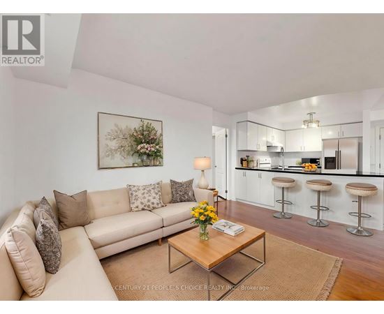 A living room with a beige couch, a coffee table, and a kitchen area in the background.