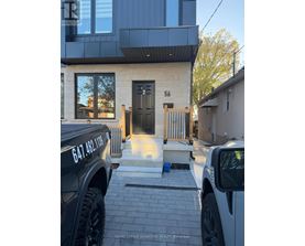 A black truck is parked in front of a house with the number 56 on the front door.