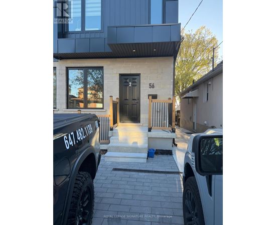 A black truck is parked in front of a house with the number 56 on the front door.