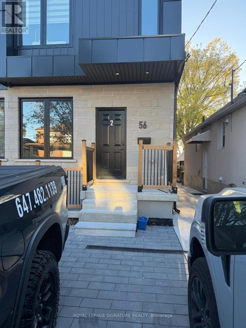 A black truck is parked in front of a house with the number 56 on the front door.