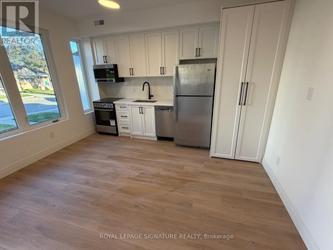 A kitchen with white cabinets and a stainless steel refrigerator.