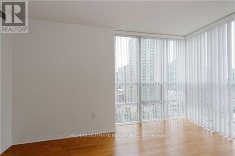 A large empty room with a view of a cityscape through the windows.