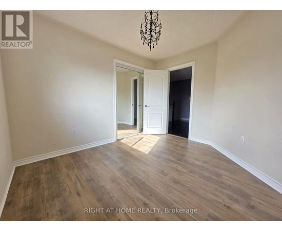 A room with wooden flooring and a chandelier hanging from the ceiling.