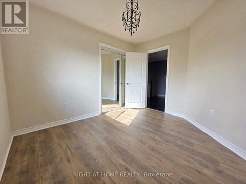 A room with wooden flooring and a chandelier hanging from the ceiling.