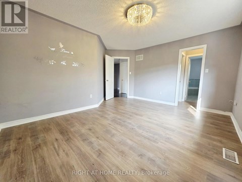 A room with wood flooring and a chandelier.