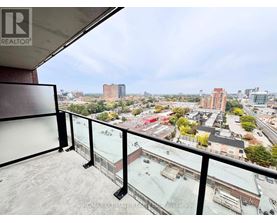 A balcony with a glass railing overlooks a cityscape.