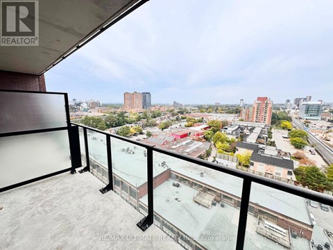 A balcony with a glass railing overlooks a cityscape.
