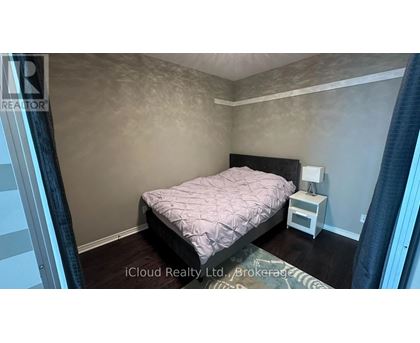 A bedroom with a bed, nightstand, and lamp.
