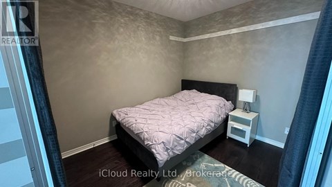 A bedroom with a bed, nightstand, and lamp.
