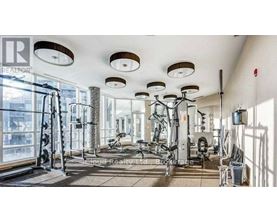 A well-lit gym with various exercise equipment and a large mirror on the wall.