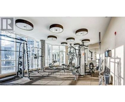 A well-lit gym with various exercise equipment and a large mirror on the wall.