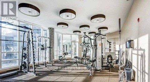 A well-lit gym with various exercise equipment and a large mirror on the wall.