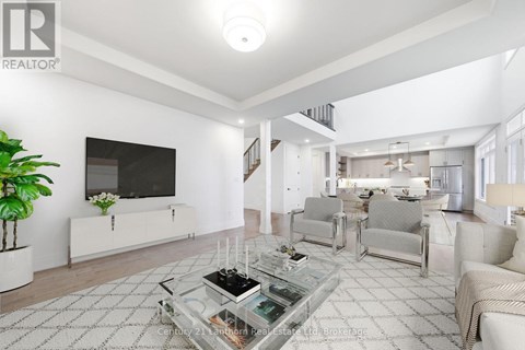 A living room with a glass coffee table and a television on the wall.